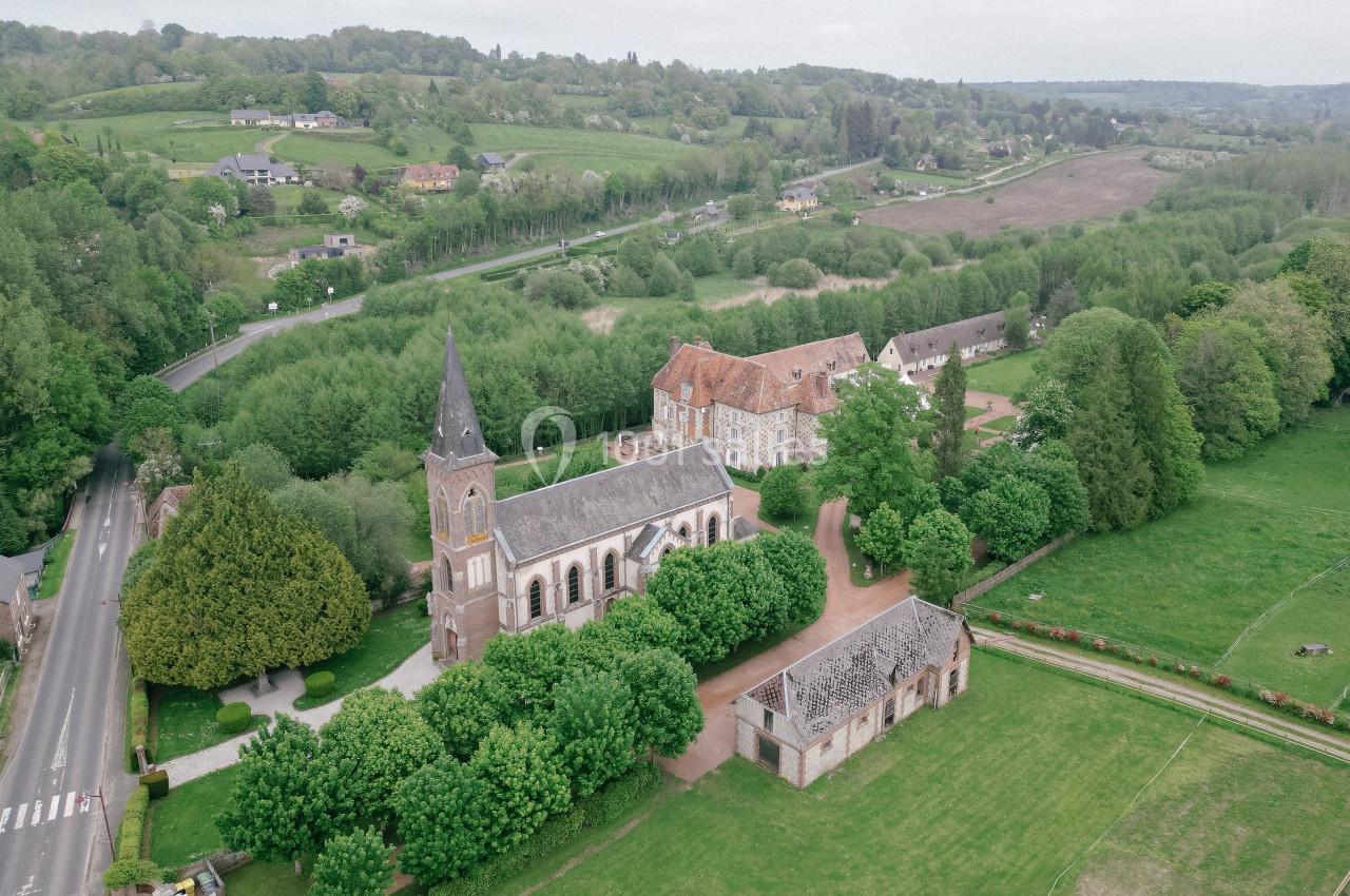 Vue aérienne d'une église entourée de bâtiments anciens, de routes et de paysages verdoyants.