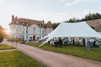 Salle spacieuse avec canapés, baby-foot, table de jeux et grandes fenêtres donnant sur un extérieur arboré.