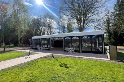 Salle spacieuse avec canapés, baby-foot, table de jeux et grandes fenêtres donnant sur un extérieur arboré.