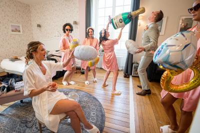 Salle spacieuse avec canapés, baby-foot, table de jeux et grandes fenêtres donnant sur un extérieur arboré.