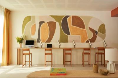 Espace intérieur moderne avec fauteuil rose, table basse en bois, sac orange et étagère murale décorative.