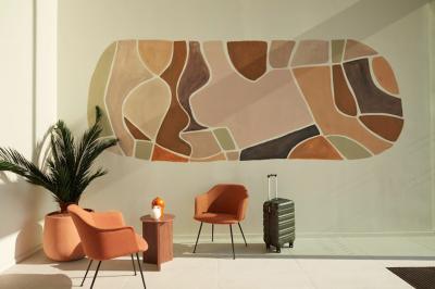 Espace intérieur moderne avec fauteuil rose, table basse en bois, sac orange et étagère murale décorative.