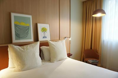 Espace intérieur moderne avec fauteuil rose, table basse en bois, sac orange et étagère murale décorative.