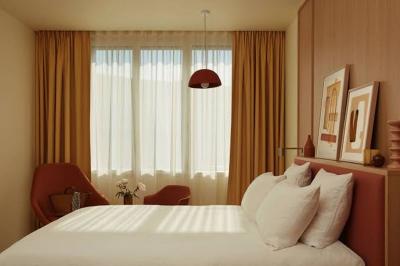 Espace intérieur moderne avec fauteuil rose, table basse en bois, sac orange et étagère murale décorative.