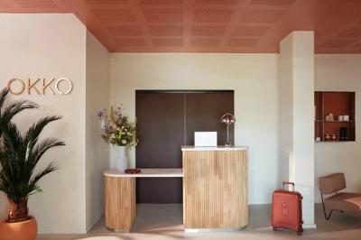 Espace intérieur moderne avec fauteuil rose, table basse en bois, sac orange et étagère murale décorative.