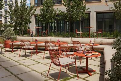 Espace intérieur moderne avec fauteuil rose, table basse en bois, sac orange et étagère murale décorative.