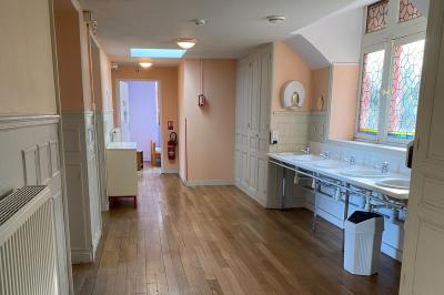 Cuisine professionnelle équipée avec plaques de cuisson, étagères, réfrigérateur, évier et équipements de sécurité visibles.