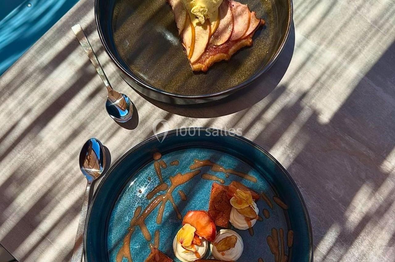 Deux assiettes de desserts sur une table ensoleillée, comprenant une tarte aux fruits et des pâtisseries décorées.