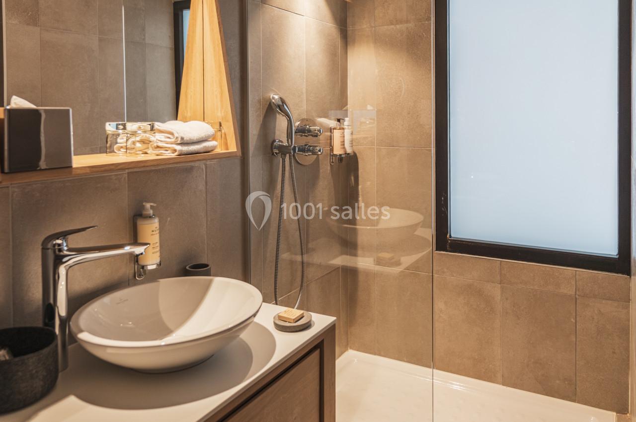 Salle de bain moderne avec douche à l'italienne, vasque sur meuble en bois et éclairage intégré.