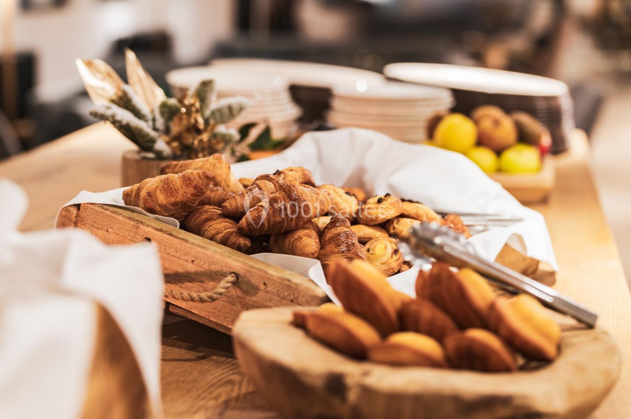 Plateau de croissants et viennoiseries disposés sur une table en bois, entourés de fruits et de décorations.