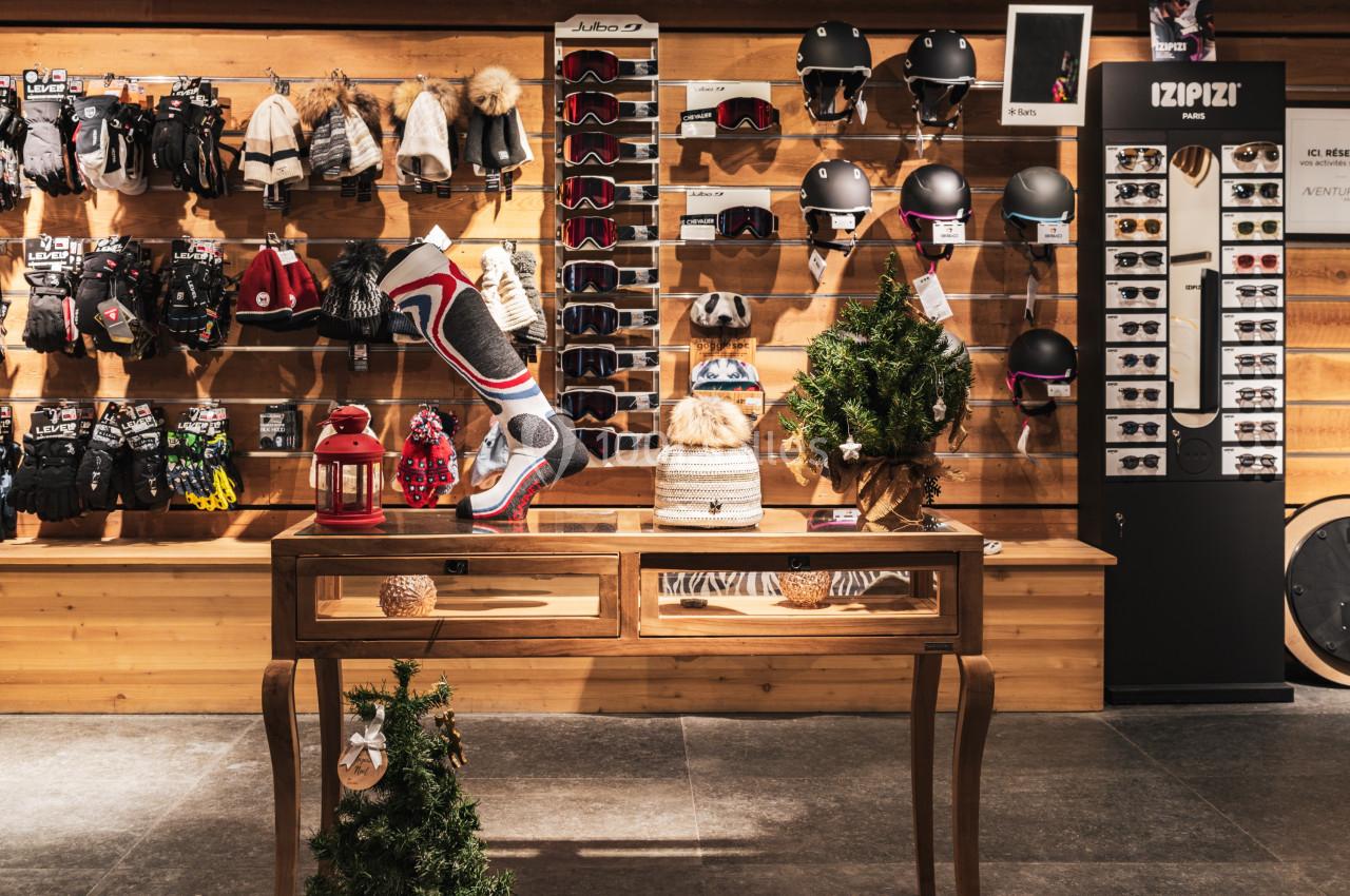 Mur d'accessoires de sports d'hiver avec gants, casques et lunettes, table décorative au premier plan.