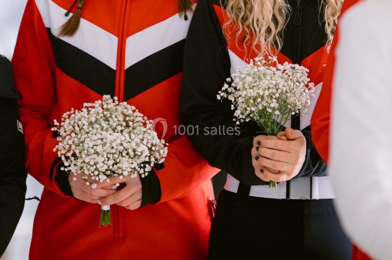 Deux personnes en tenue rouge et noire tiennent des bouquets de gypsophiles blanches dans leurs mains.