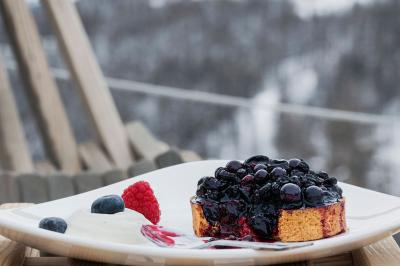 Un dessert composé d'un gâteau aux fruits rouges, accompagné de crème et de baies, présenté sur une terrasse en hiver.