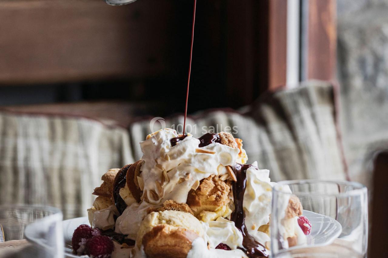 Assiette de profiteroles garnies de crème chantilly, framboises et nappées de chocolat liquide.