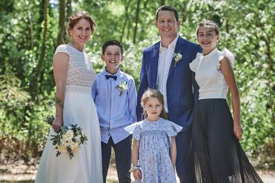 Un grand groupe de personnes souriantes levant les bras, rassemblées dans un parc pour une célébration.