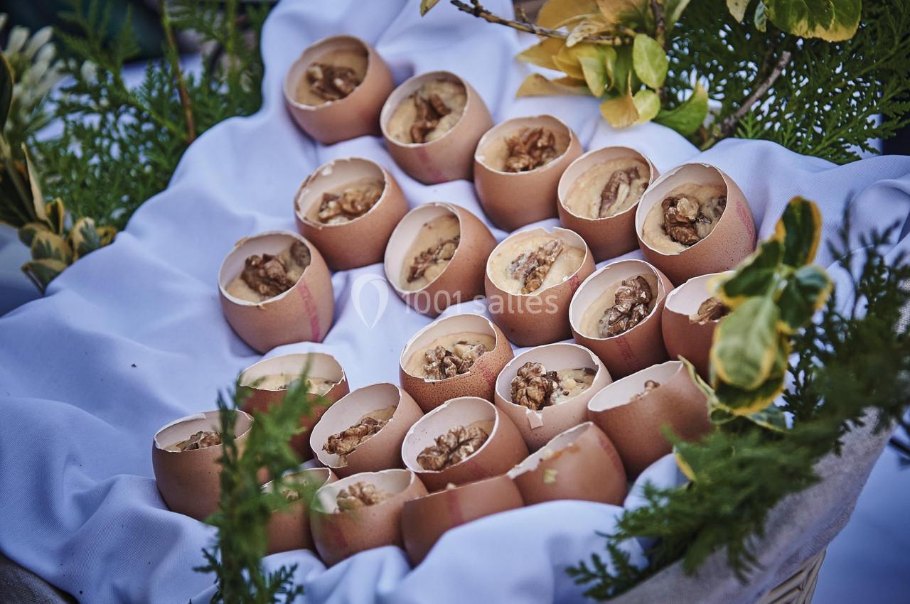 Coquilles d'œufs remplies d'une préparation, disposées sur un tissu blanc dans un panier entouré de verdure.