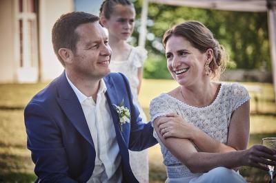 Un grand groupe de personnes souriantes levant les bras, rassemblées dans un parc pour une célébration.