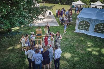 Un grand groupe de personnes souriantes levant les bras, rassemblées dans un parc pour une célébration.