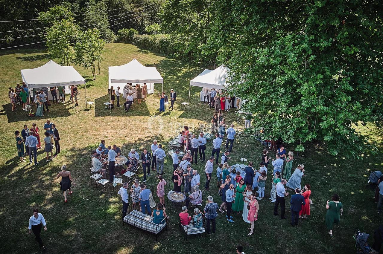 Groupe de personnes rassemblées dans un jardin avec des tentes blanches, lors d'un événement en plein air.