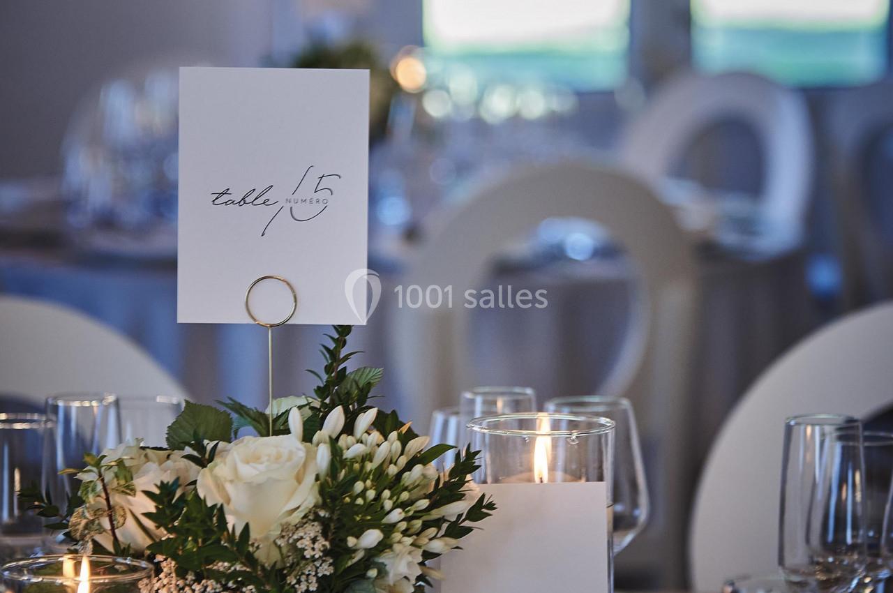 Décoration de table élégante avec fleurs blanches, bougies allumées et carte indiquant le numéro de table 15.