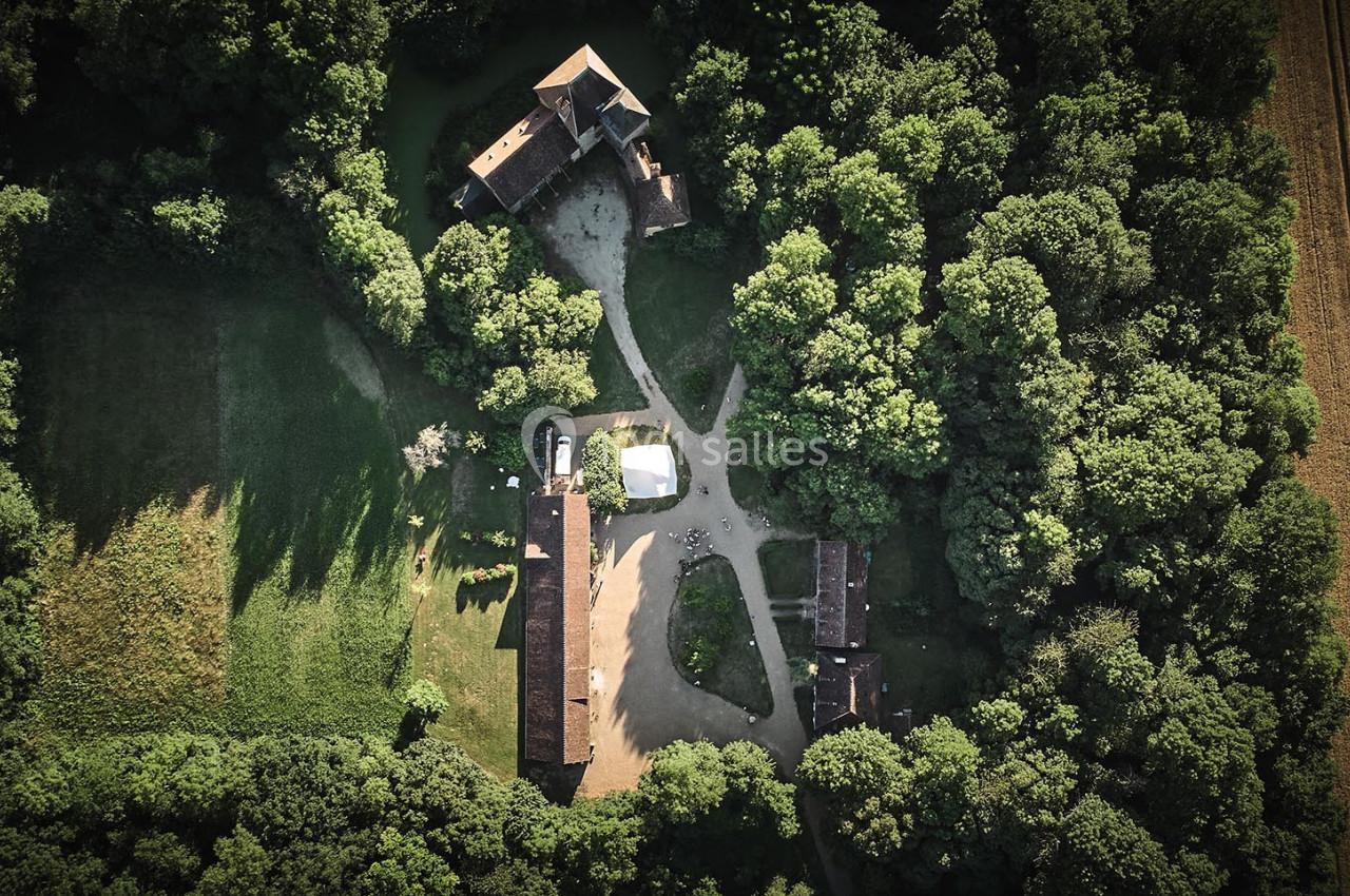 Vue aérienne d'un domaine entouré de forêt avec plusieurs bâtiments et chemins en terre.