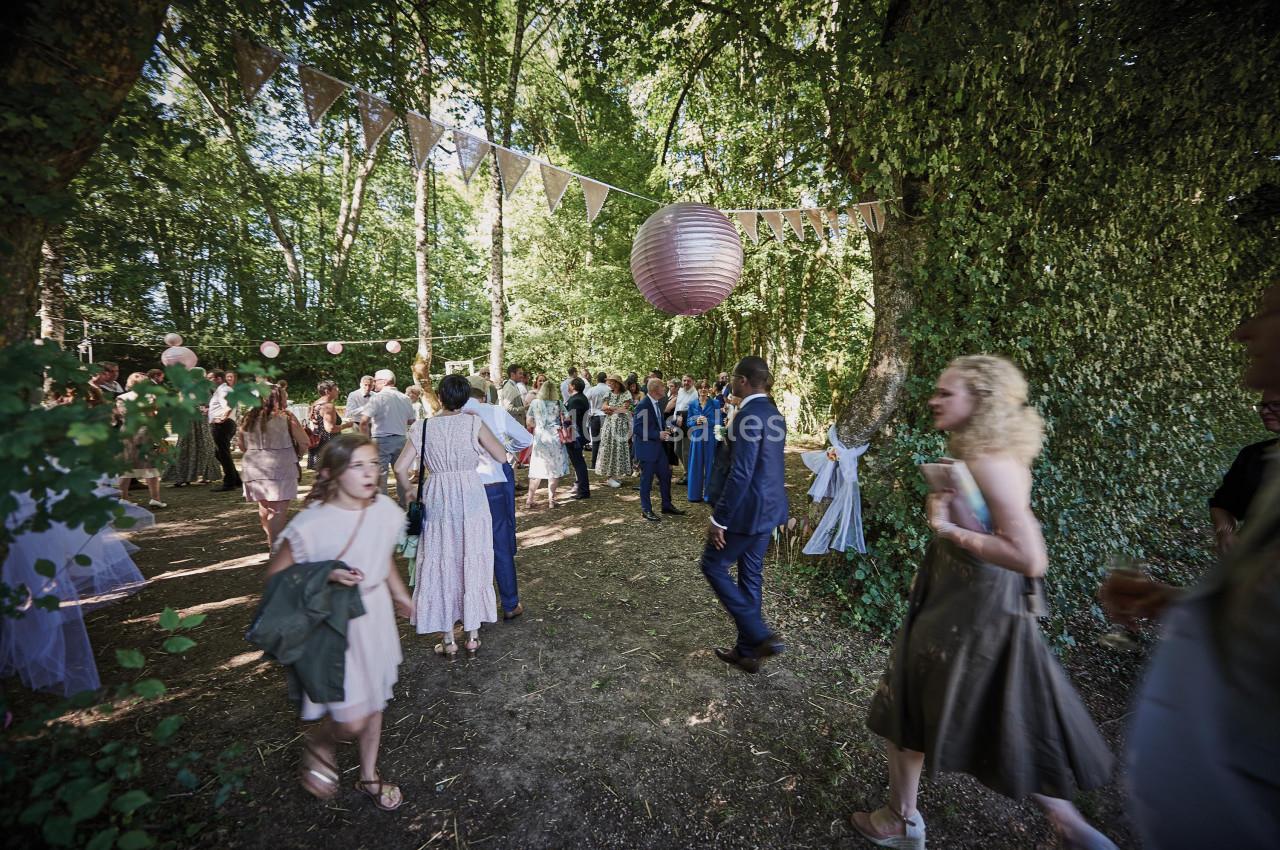 Groupe de personnes rassemblées dans une clairière décorée de guirlandes et lanternes pour une fête en plein air.