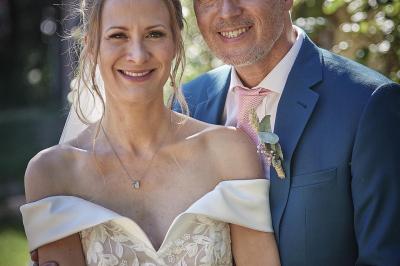Un grand groupe de personnes souriantes levant les bras, rassemblées dans un parc pour une célébration.
