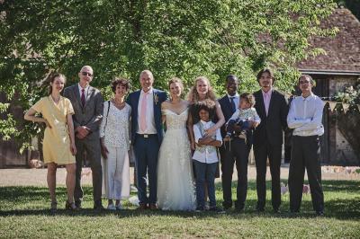 Un grand groupe de personnes souriantes levant les bras, rassemblées dans un parc pour une célébration.