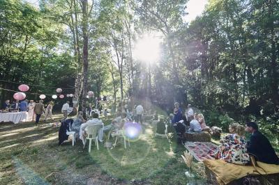 Un grand groupe de personnes souriantes levant les bras, rassemblées dans un parc pour une célébration.