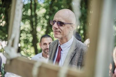 Un grand groupe de personnes souriantes levant les bras, rassemblées dans un parc pour une célébration.