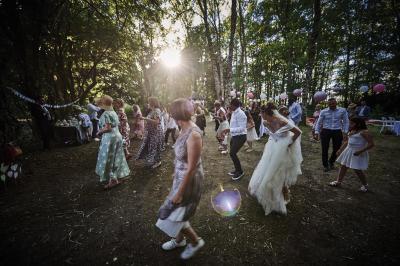 Un grand groupe de personnes souriantes levant les bras, rassemblées dans un parc pour une célébration.