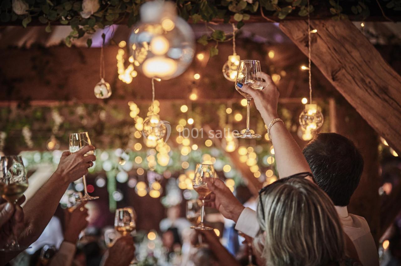 Des convives lèvent leurs verres sous une décoration lumineuse et végétale lors d'une célébration festive.