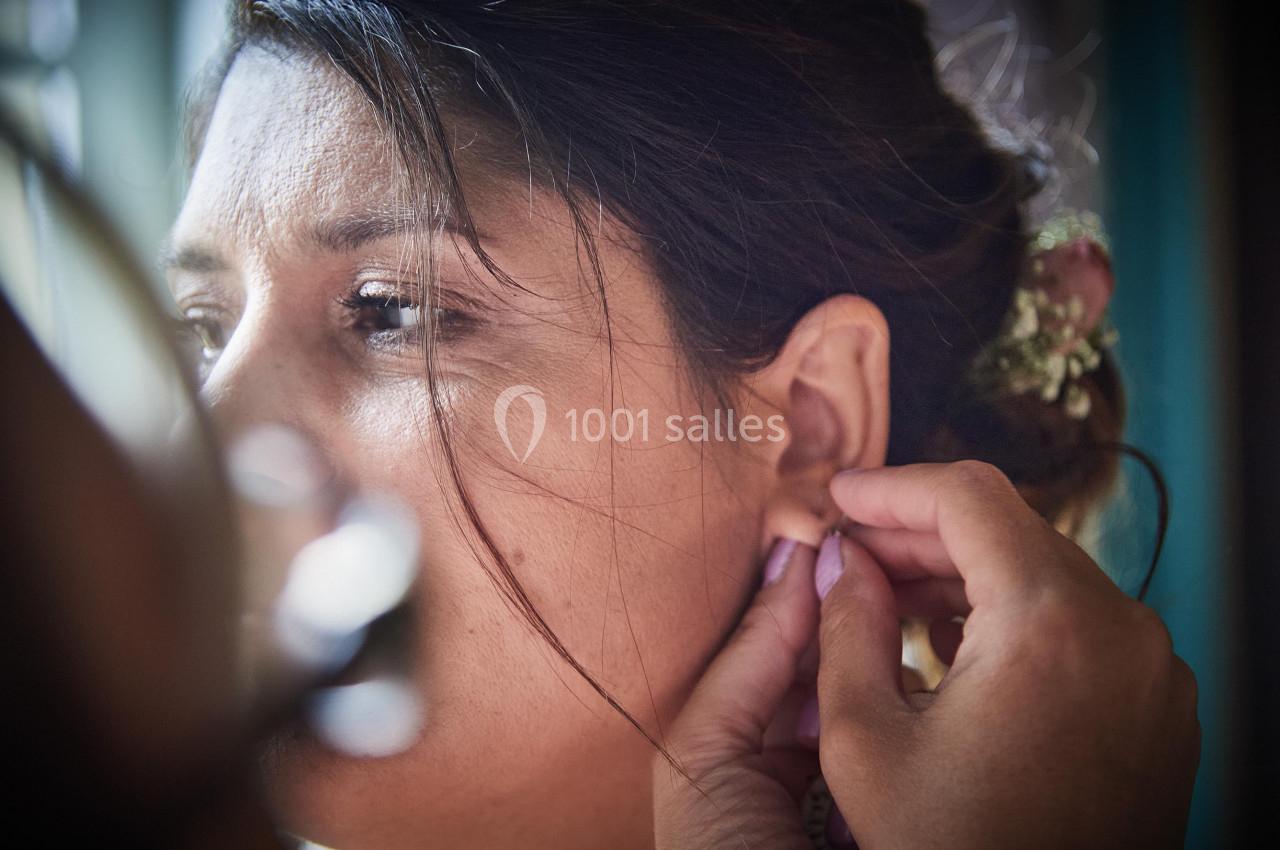 Une femme se fait aider pour mettre une boucle d'oreille, avec des détails de cheveux et de lumière naturelle.