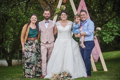 Un grand groupe de personnes souriantes levant les bras, rassemblées dans un parc pour une célébration.
