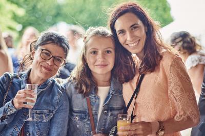 Un grand groupe de personnes souriantes levant les bras, rassemblées dans un parc pour une célébration.