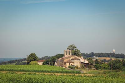 Vue d'un village rural avec une église en pierre entourée de champs verdoyants sous un ciel dégagé.