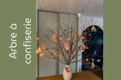 Arrangement floral avec des fleurs roses et blanches, entouré de petits sachets cadeaux en tissu et jute sur une table.