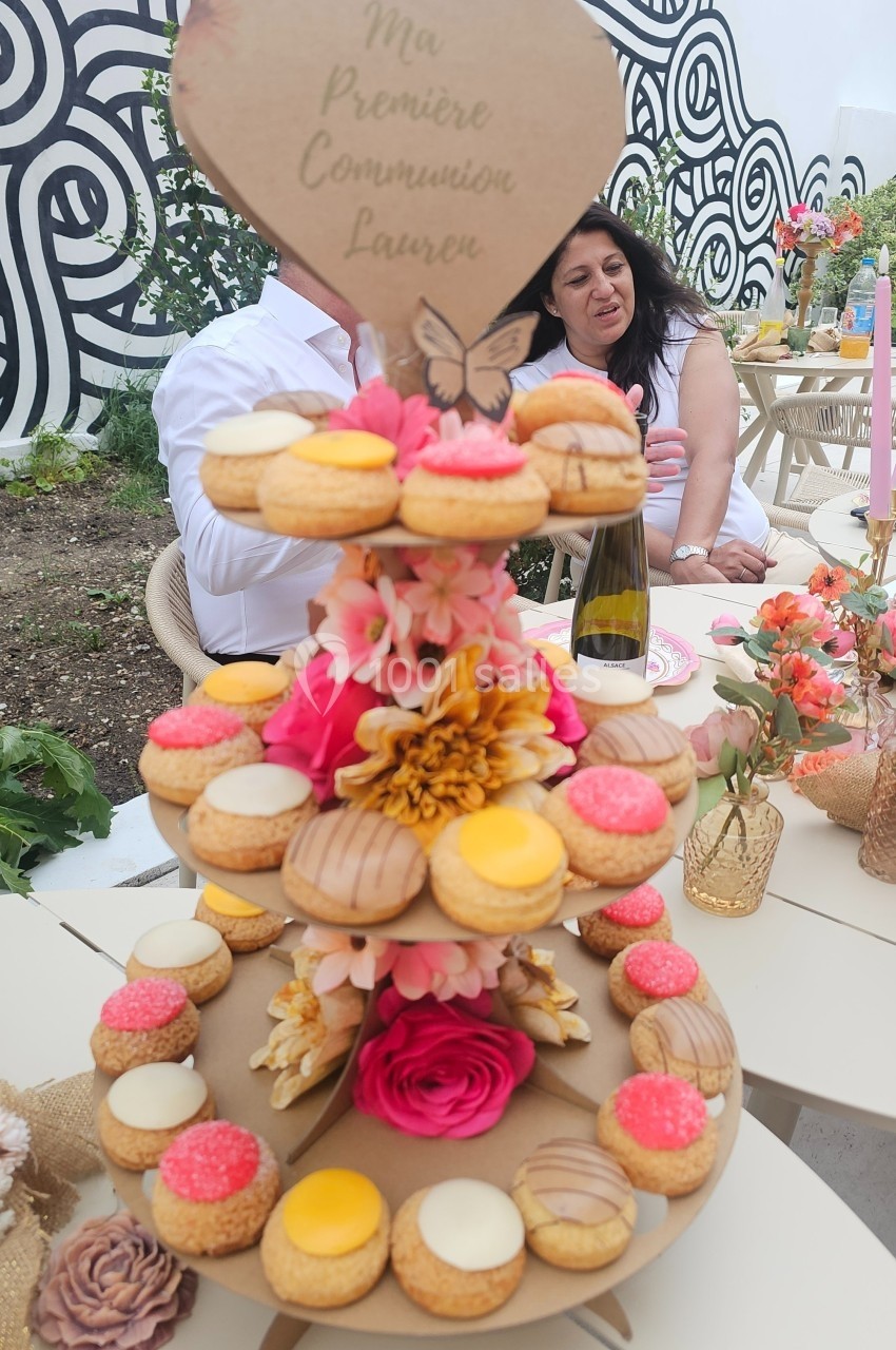 Présentoir en bois décoré de fleurs et de choux colorés, lors d'une célébration en extérieur.