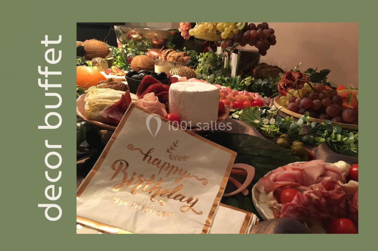 Buffet décoratif avec fromages, charcuteries, fruits et serviette ’Happy Birthday’ sur une nappe élégante.