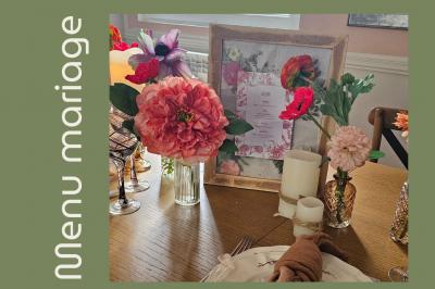 Arrangement floral avec des fleurs roses et blanches, entouré de petits sachets cadeaux en tissu et jute sur une table.