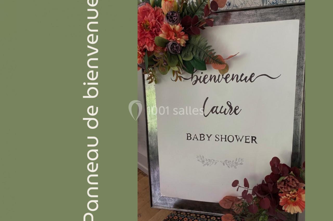 Panneau de bienvenue pour une baby shower, décoré de fleurs colorées sur un fond vert.