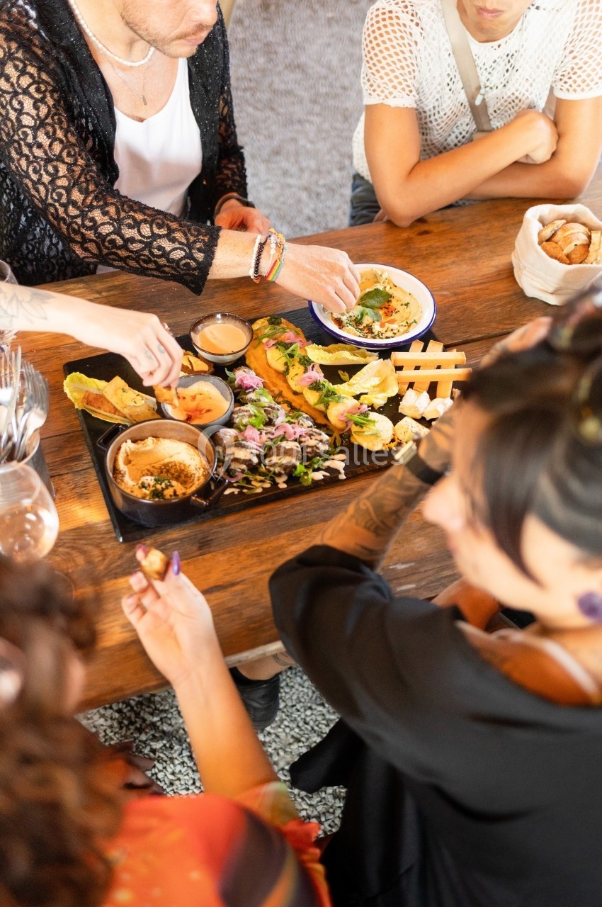 Personnes partageant un plateau de mezzés variés sur une table en bois dans un cadre convivial.