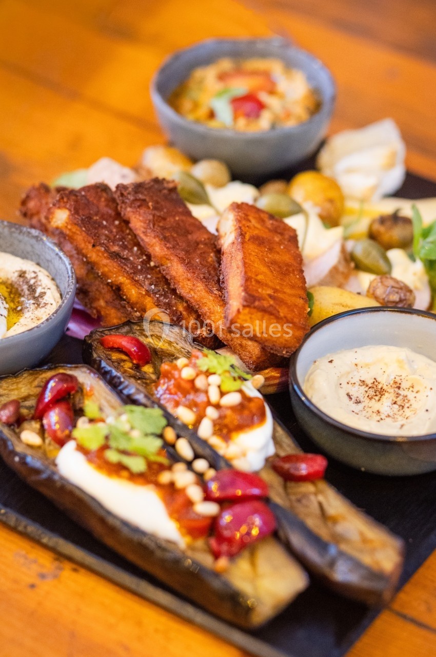 Assiette composée de légumes grillés, halloumi, sauces variées et accompagnements sur une table en bois.