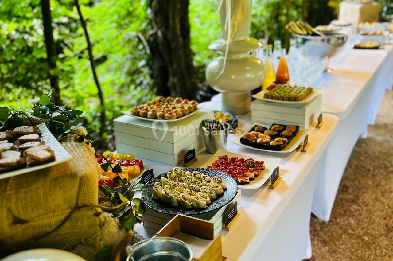 Buffet en plein air avec une variété de plats et de desserts disposés sur une longue table blanche.