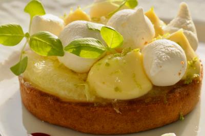 Façade illuminée d'un bâtiment élégant au crépuscule, avec un jardin et des invités rassemblés devant.