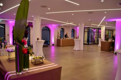 Façade illuminée d'un bâtiment élégant au crépuscule, avec un jardin et des invités rassemblés devant.