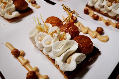 Façade illuminée d'un bâtiment élégant au crépuscule, avec un jardin et des invités rassemblés devant.