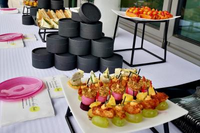 Façade illuminée d'un bâtiment élégant au crépuscule, avec un jardin et des invités rassemblés devant.