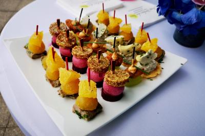 Façade illuminée d'un bâtiment élégant au crépuscule, avec un jardin et des invités rassemblés devant.