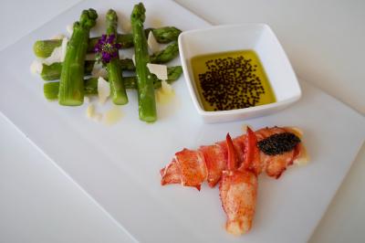 Façade illuminée d'un bâtiment élégant au crépuscule, avec un jardin et des invités rassemblés devant.